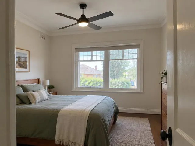 Bedroom with a ceiling fan, window and bedside furniture in a home interior in Holmesville