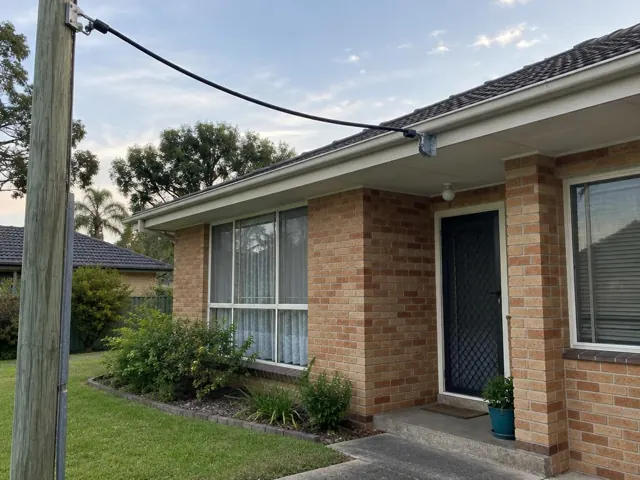 Overhead service cable and wall bracket on a brick house exterior in Edgeworth